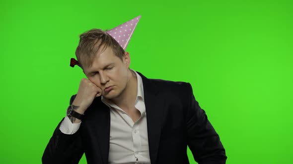 Drunk Sleepy Young Businessman with Hangover in Festive Cap Falling Asleep