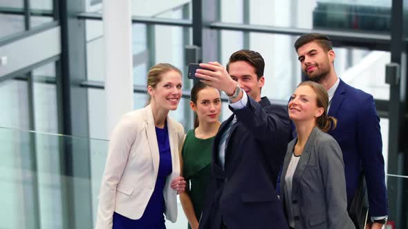 Business executives taking selfie on mobile phone in corridor