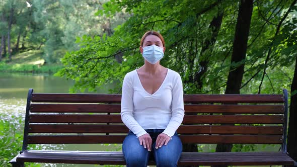 Pandemic, Coronavirus Quarantine. Young Woman Sits on a Park Bench Alone During an Epidemic