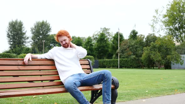 Tired Man with Neck Pain Sitting in Park on Bench