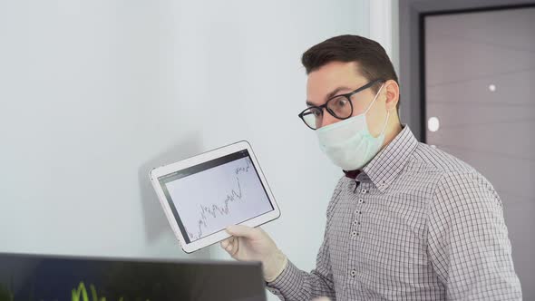 Young businessman wear face mask, holding video call with clients on laptop, giving online education