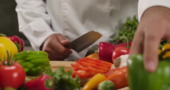 Chef is Slicing a Green Paprika in the Kitchen