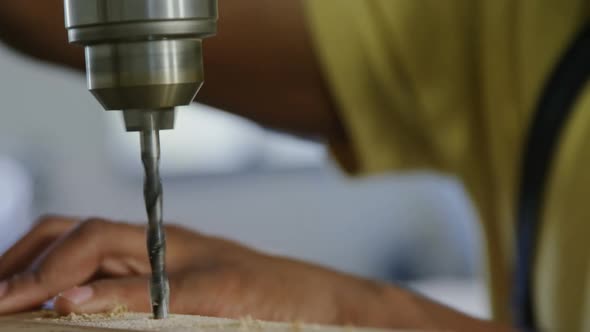 Carpenter drilling wooden plank with machine in workshop 4k