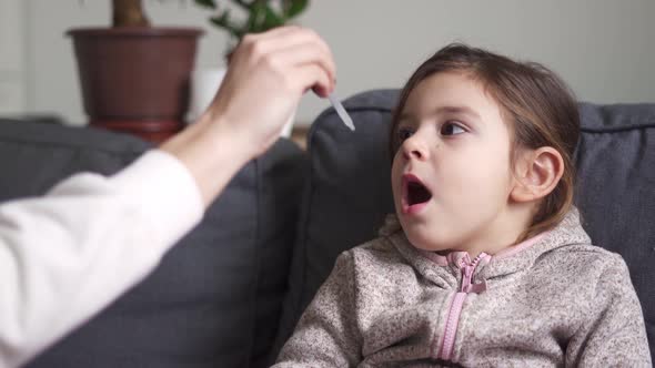 Portrait of Caucasian Preschool Girl Taking Vitamins with Drops at Home