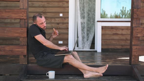 A Man Working on a Laptop Talking on the Phone Eating a Sandwich and Drinking Tea Sitting on the