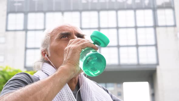 Slow motion shot of senior athletic man drinking from bottle