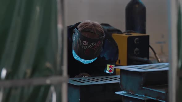 Industrial Worker in Protective Mask Using Modern Welding Machine for Welding Metal Construction on
