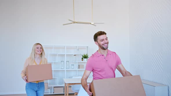 Excited blonde young woman and bearded guy stack cardboard boxes on large pile