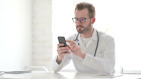 Attractive Doctor Using Smartphone in Office