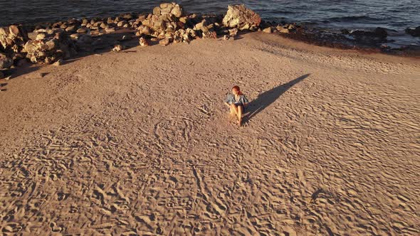 Flight Up: Serious LGBT Woman Wears Rainbow Bracelet and Sits at Cape Kolka with View Over Sea