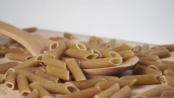 Raw uncooked integral whole pasta in a wood spoon