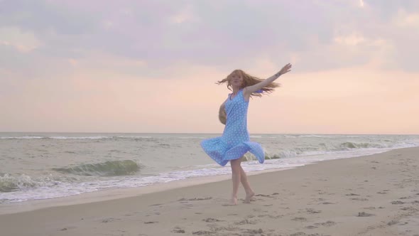 Carefree Woman Dancing on the Sunset on the Sea Beach. Girl Rotate with a Straw Hat in His Hand