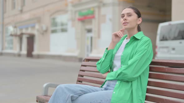 Pensive Hispanic Woman Thinking While Sitting Outdoor on Bench