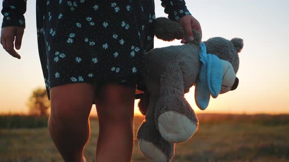 Little Girl in Dress Holding Teddy Bear Toy at Sunset. Concept of a Child Dream.