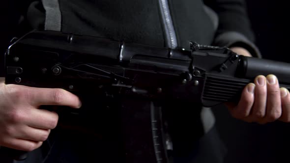 A Bandit Stands with a Gun in Hand on a Black Background. Close-up Panorama From Left To Right