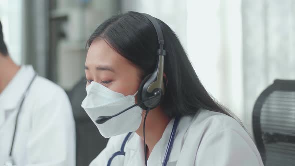 Close Up Of An Asian Woman Doctor In Masks Working As Call Centre Agent Speaking To Customer