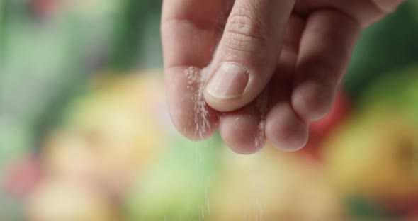 Close Up Of Male Fingers Salting With A Fine Salt And Food On The Background