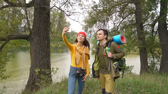 Young Attractive Couple Tourists Take a Selfie in the Autumn Forest.