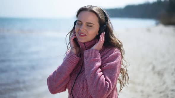 Portrait of Happy Smiling Woman Dancing in Slow Motion on Sandy Beach Listening to Music in