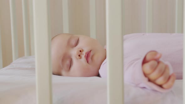 Cute Little Baby Sleeps Sweetly in His Crib and Sees Colorful Dreams in Bedroom While Sleeping.