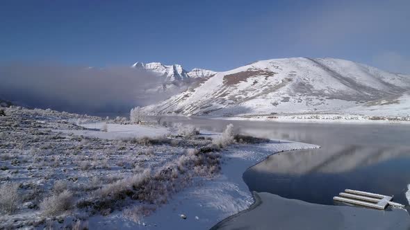 Aerial view fling over snowy white landscape next to reservoir