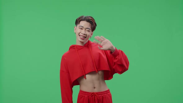 Happy Asian Transgender Male Waving Hands And Looking At Camera In The Green Screen Studio