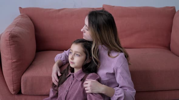 Mom and Daughter in Purple Dresses Sitting on Couch at Home on Christmas Day