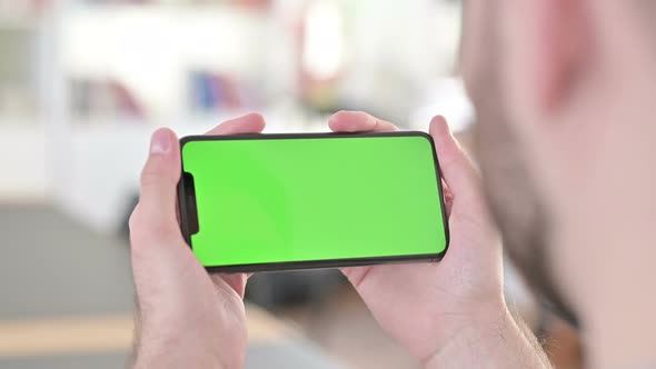 Rear View of Man Streaming Video on Chroma Key Smartphone Screen