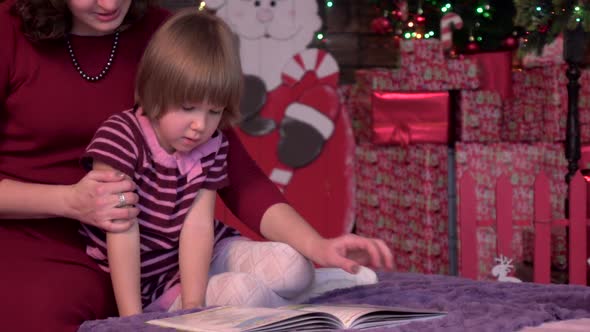 Young Mother Is Reading Book with Her Daughter