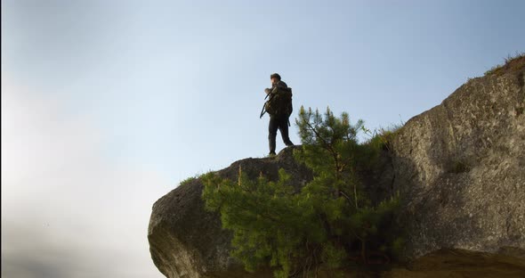 The Guy is Climbing to the Edge of a Large Rock and is Happy with the Scenery That He Sees