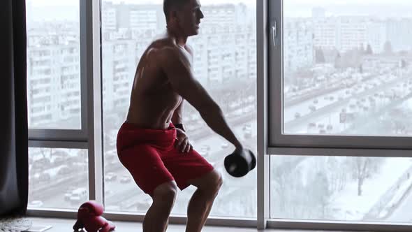 Muscular Shirtless Man Doing Situps and Pumping Up His Muscles with Dumbbells in His Hand