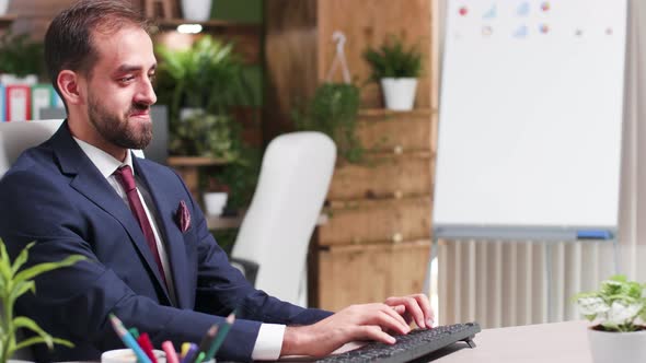 Dolly Shot of Young CEO at His Desk Working at the Computer