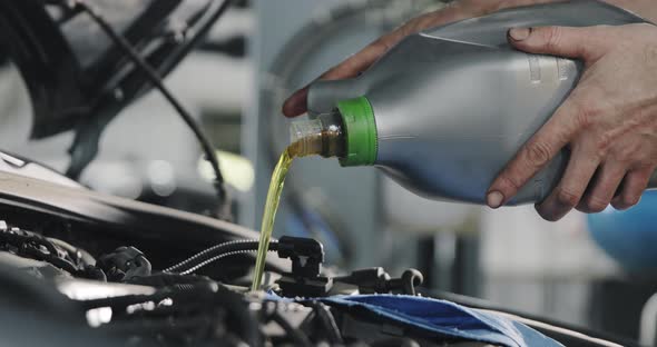 Mechanic's Hands. Engine Oil Flows From The Canister Into The Engine Of A Car.