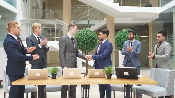 Arabic and Caucasian Businessmen in Tuxedos Shaking Hands After Negotiation