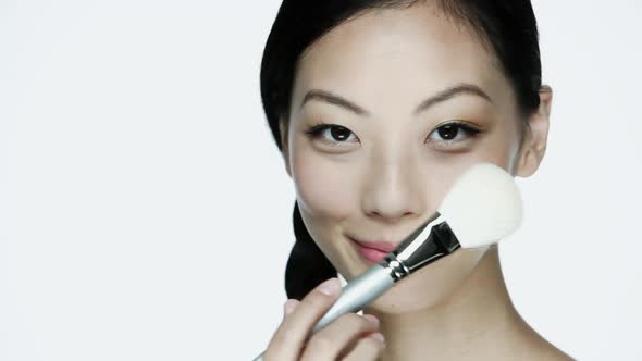 Young woman using make up brush on face