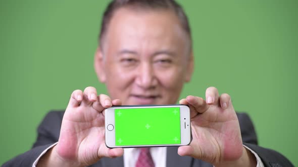Mature Japanese Businessman Showing Phone To Camera