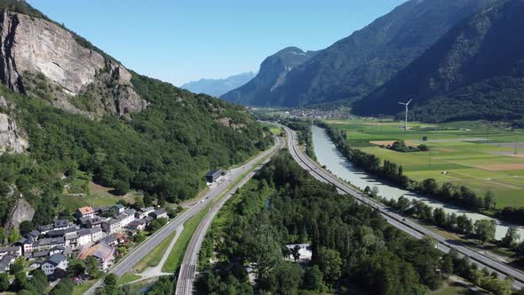 drone view through the valley in Valais with a motorway, a motorway, the river "Rhone" and a small v