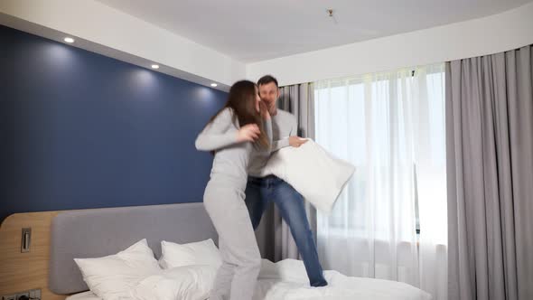 Happy Young Romantic Family Couple Playing Pillow Fight on Bed