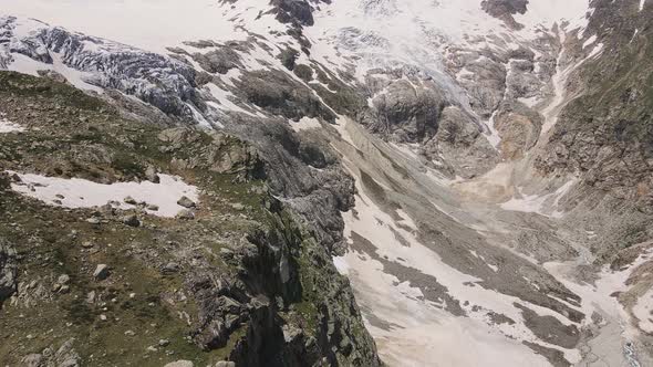 Glacier Covered with Stone Rocks Deep Cracks and Small Waterfalls