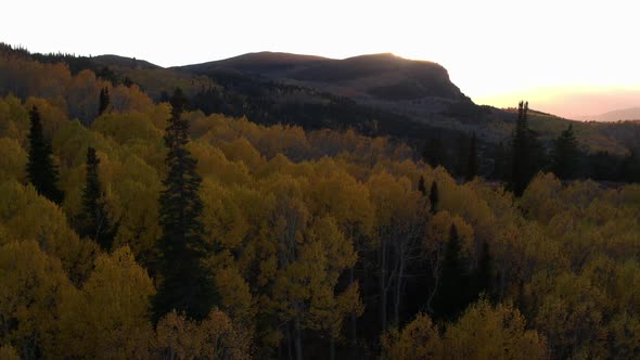 Aerial view of the sun setting on a beautiful mountainside in the fall.