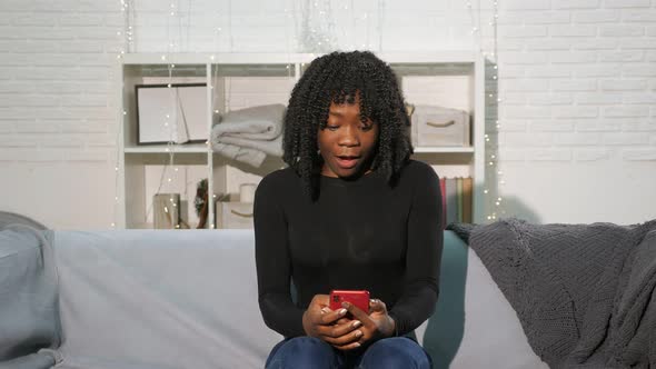 African American Girl Looks at Smartphone and Becomes Happy