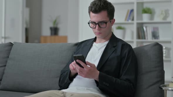 Young Male Designer Using Smartphone at Home