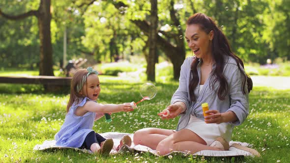 Mother with Daughter Blowing Soap Bubbles at Park