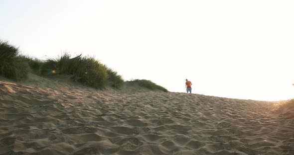 Runner jogging through sand dunes at sunrise