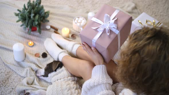 Young Woman Holding Gift Box Relaxing At Home With Dog, Cozy Winter Atmosphere