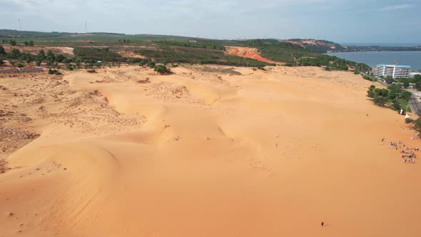 aerial dolly left of red desert sand dunes surrounded by trees in Mui Ne Vietnam