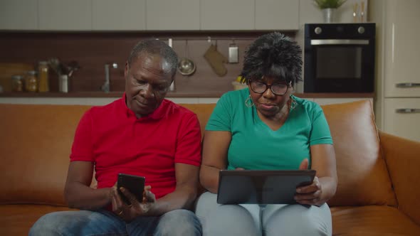 Senior African Couple Networking with Gadgets Indoor