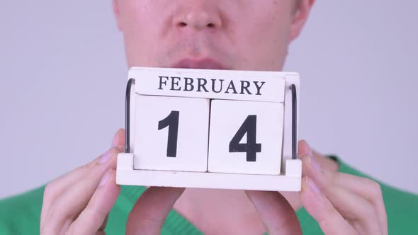 Hands of Young Man Holding Calendar Block Ready for Valentine's Day