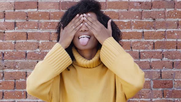 Cheerful Young African American Woman Covers Her Face with Her Hands