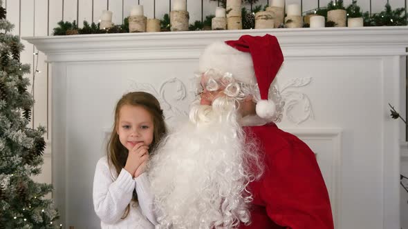 Undecided Little Girl on Santa Claus Lap Thinking About Her Present